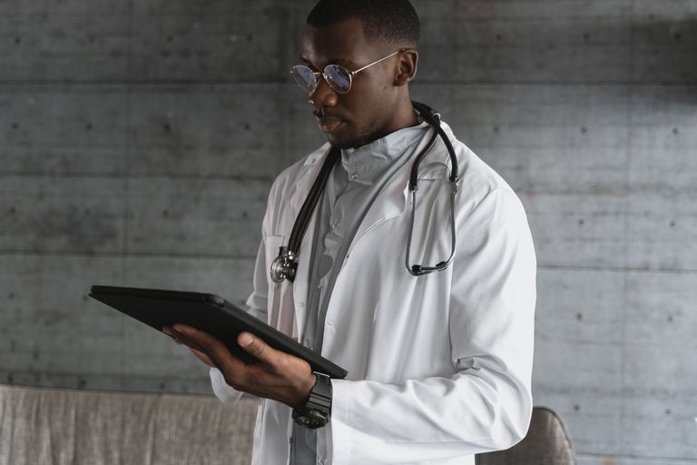 Use of Technology in Hospitals A healthcare professional using a tablet indoors, wearing a white coat and stethoscope.