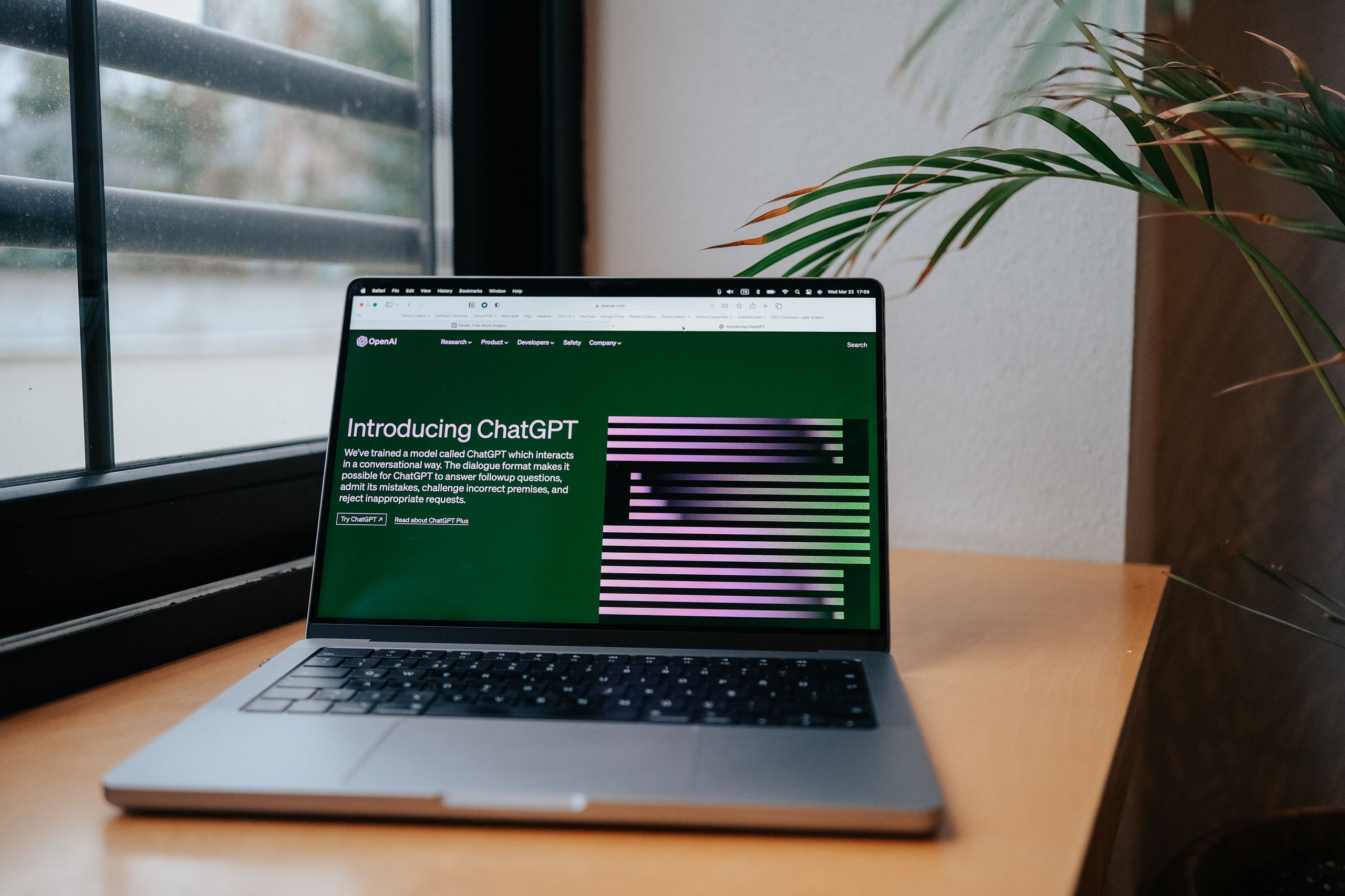 Best AI Productivity Tools A laptop displaying ChatGPT on a desk by a window, featuring a modern home office setup.