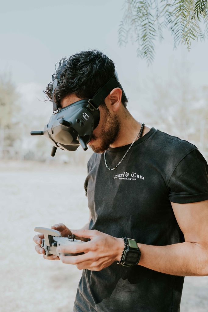 A man using VR goggles and a controller outdoors, showcasing modern technology.