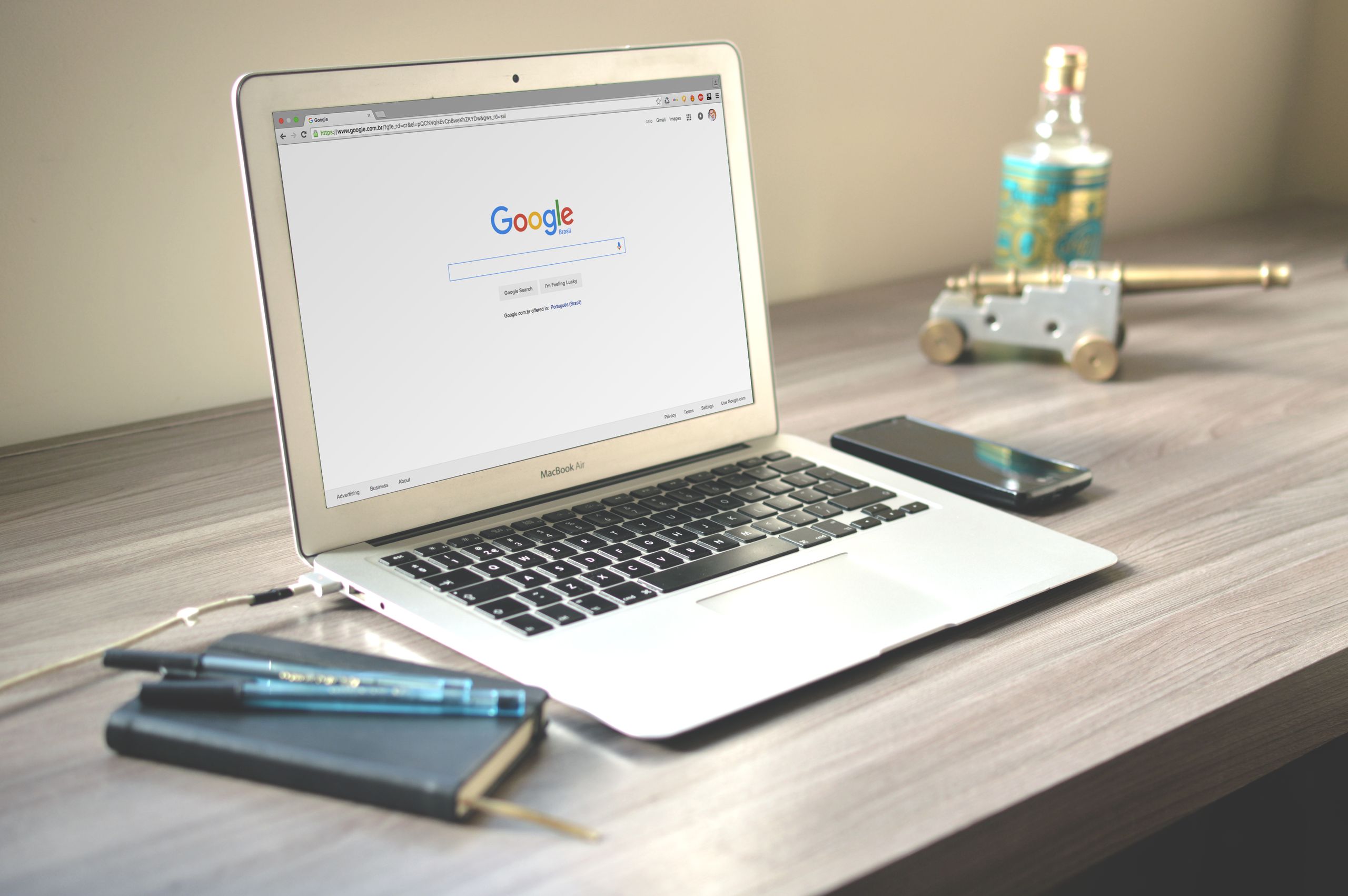 Best Free Tech Tools Every Website Owner Should Know in 2026 A neat workspace featuring a laptop displaying Google search, a smartphone, and a notebook on a wooden desk.