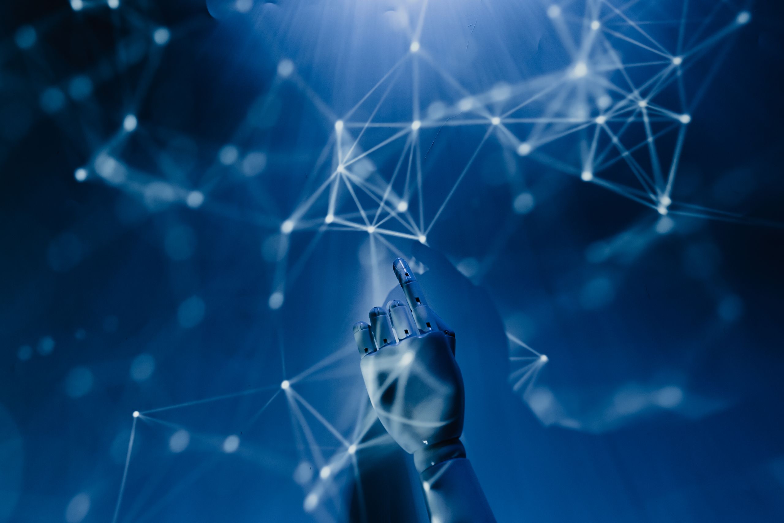 How AI Is Helpful A robotic hand reaching into a digital network on a blue background, symbolizing AI technology.