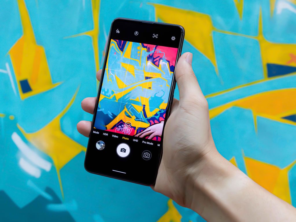 A smartphone captures vibrant abstract graffiti art, showcasing creativity and technology.