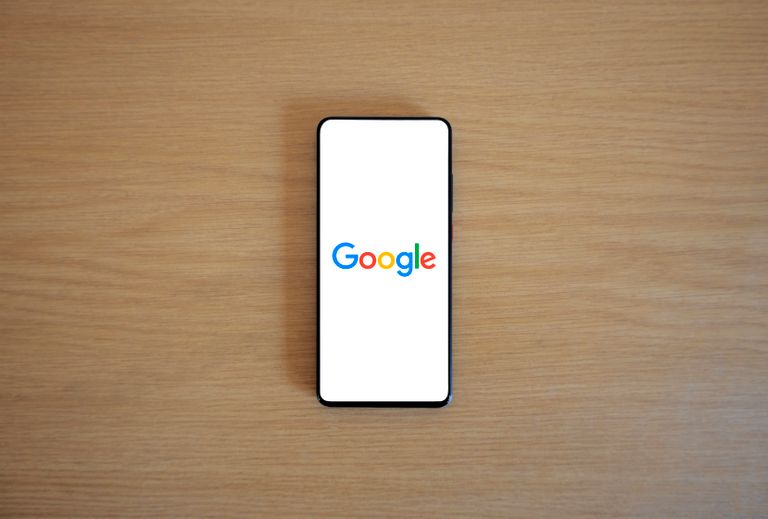 Google Pixel 11 Series: The New Era of AI Smartphones A smartphone displaying the Google homepage on a wooden surface, viewed from above.