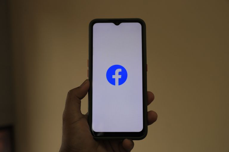How to Run a Small Business Successfully on Facebook A smartphone held in hand showing the Facebook logo on its screen.