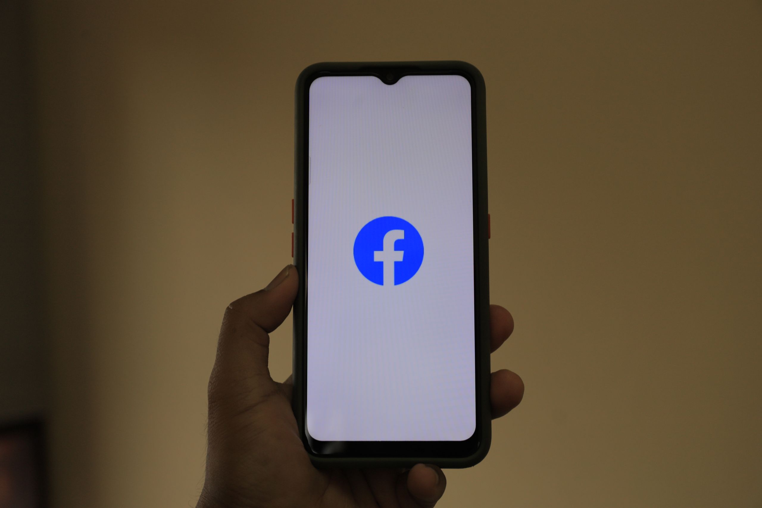 How to Run a Small Business Successfully on Facebook A smartphone held in hand showing the Facebook logo on its screen.