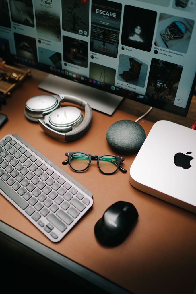 A stylish workspace featuring a Tech Gadgets keyboard, mouse, eyeglasses, headphones, and a screen displaying digital content.