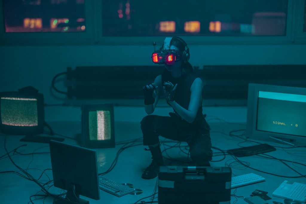 A woman crouching with VR headset in a sci-fi room filled with digital screens.