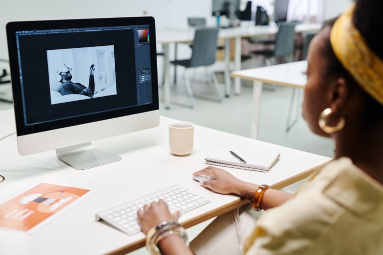 What Is Graphic and Video Designing A woman using a computer for image editing in a bright, modern office setting.