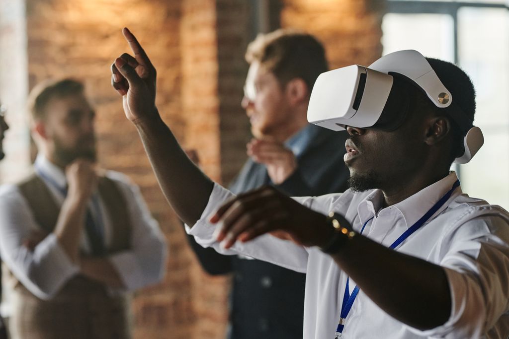 African American man using VR Mixed Reality headset in a business meeting with colleagues in the background.