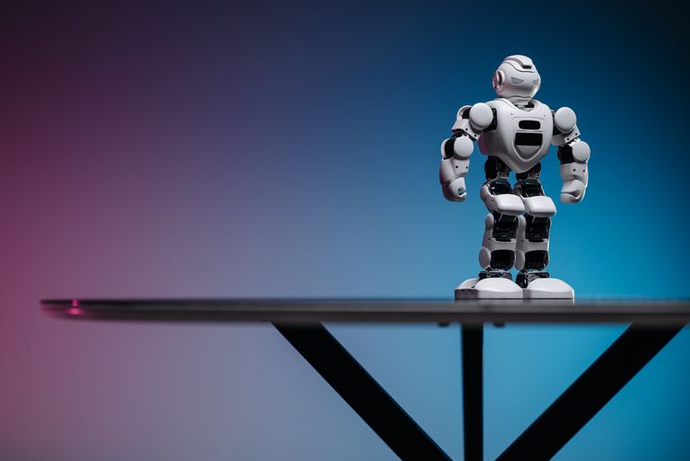 AI Tools Close-up of a futuristic robot toy on a table with a gradient blue-pink background.