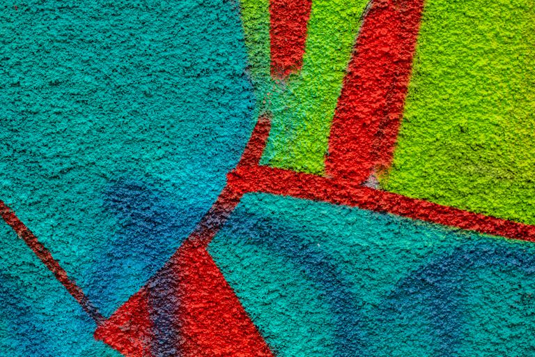 Close-up of colorful graffiti on a textured wall showcasing vibrant hues and abstract patterns.
