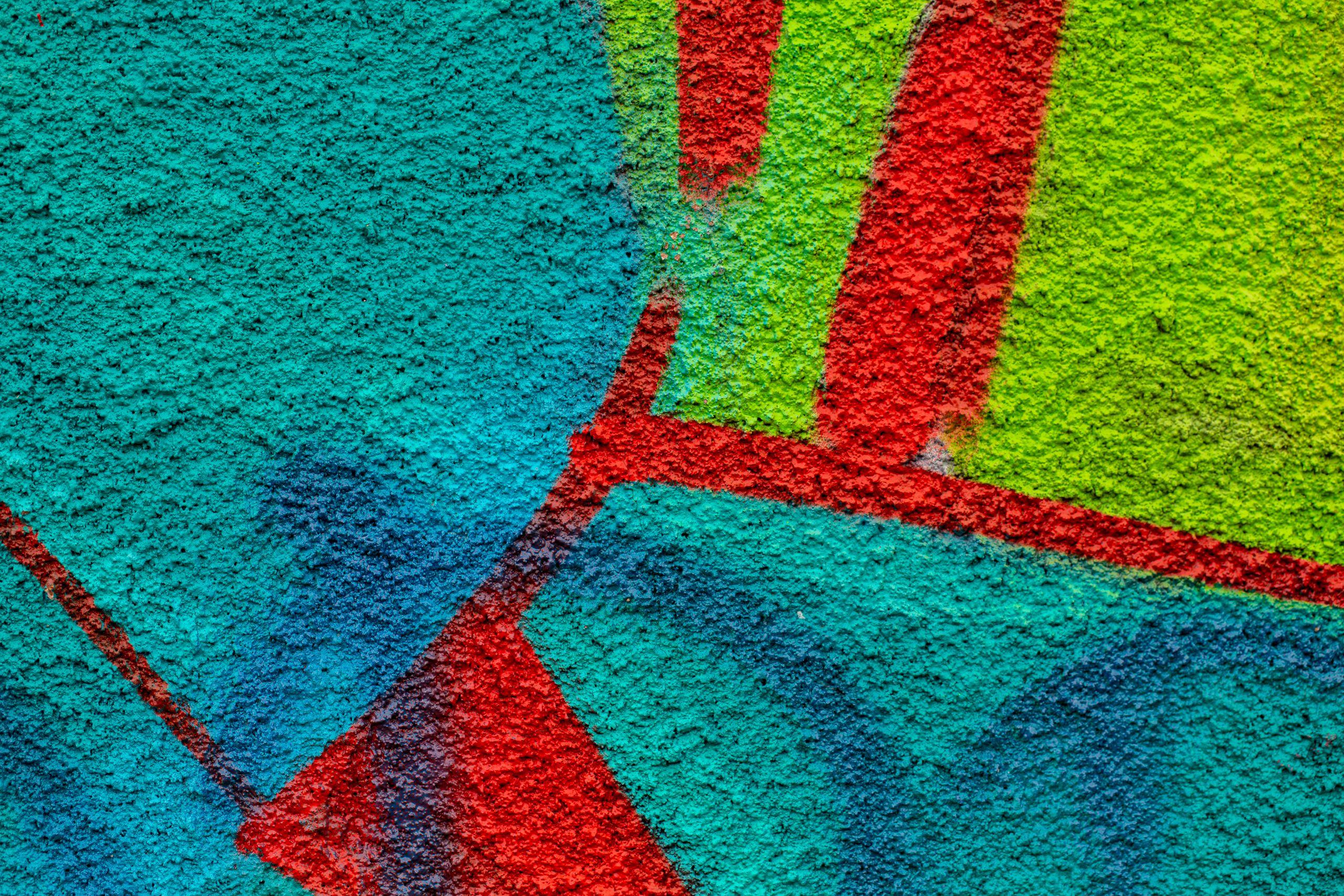Close-up of colorful graffiti on a textured wall showcasing vibrant hues and abstract patterns.