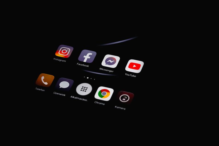 What Is App Designing Close-up of smartphone displaying popular social media apps in dim lighting.