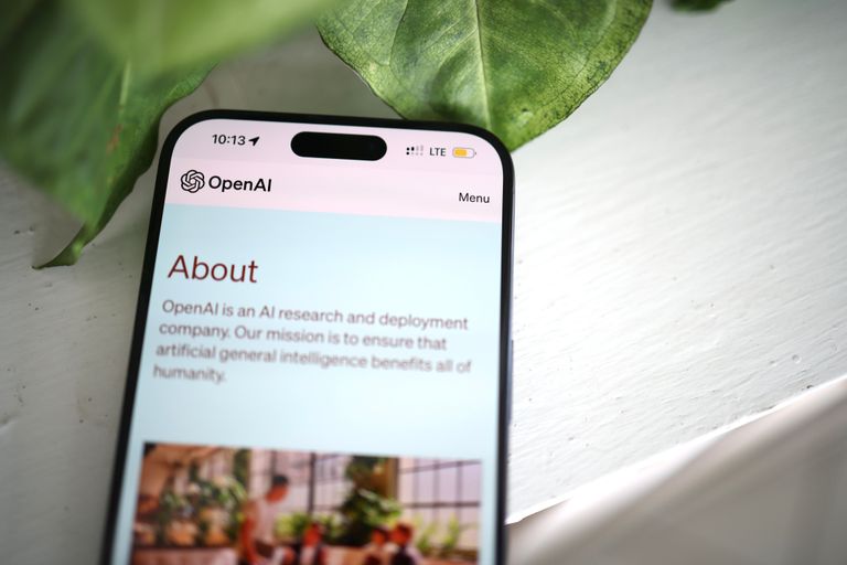 AI Agents Are Changing Online Shopping Close-up shot of a smartphone screen showing the OpenAI website with greenery in the background.