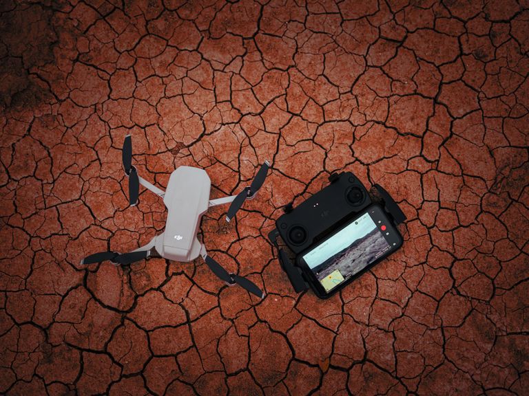 Drone with controller on a dry, cracked ground illustrating modern technology usage in harsh environments.
