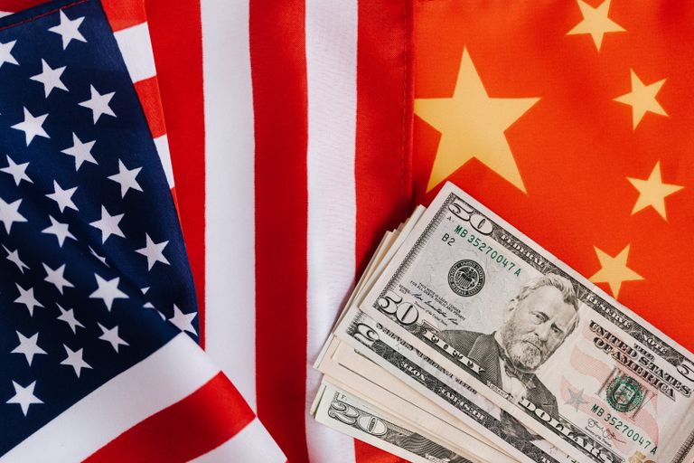 China vs. USA From above of United States banknotes placed on national flags of America and China illustrating international trade concept