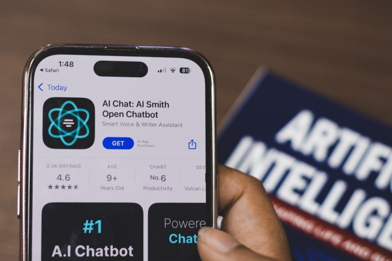 AI Agents vs. Chatbots Hand holding a smartphone with AI chatbot app, emphasizing artificial intelligence and technology.