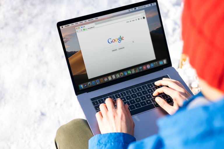 How to Optimize Your Website for Google AI Overviews Individual typing on a laptop outdoors with snow, accessing the internet.