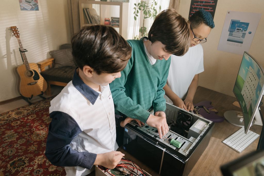 Kids working together assembling a computer indoors, showcasing teamwork.