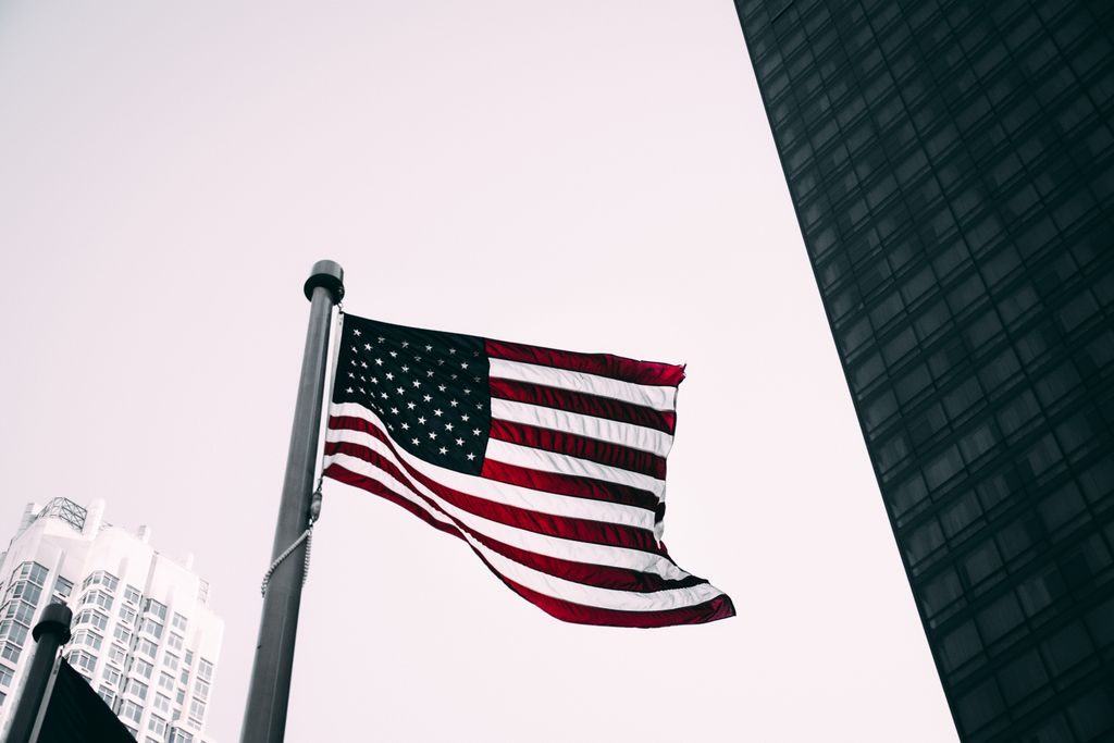Low angle view of the American flag waving against modern skyscraper background.