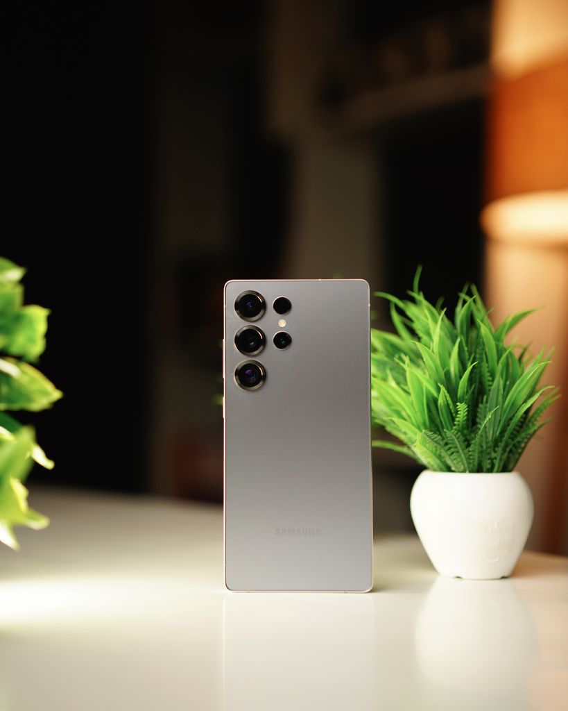 Samsung Smartphones  Modern smartphone standing on a desk with green potted plants in a warm indoor setting.
