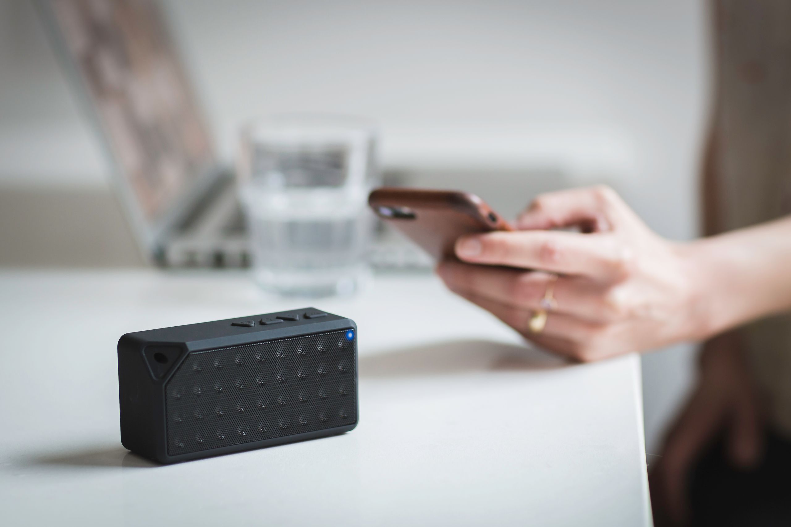 Person connecting a smartphone to a wireless speaker indoors, foreground focus.