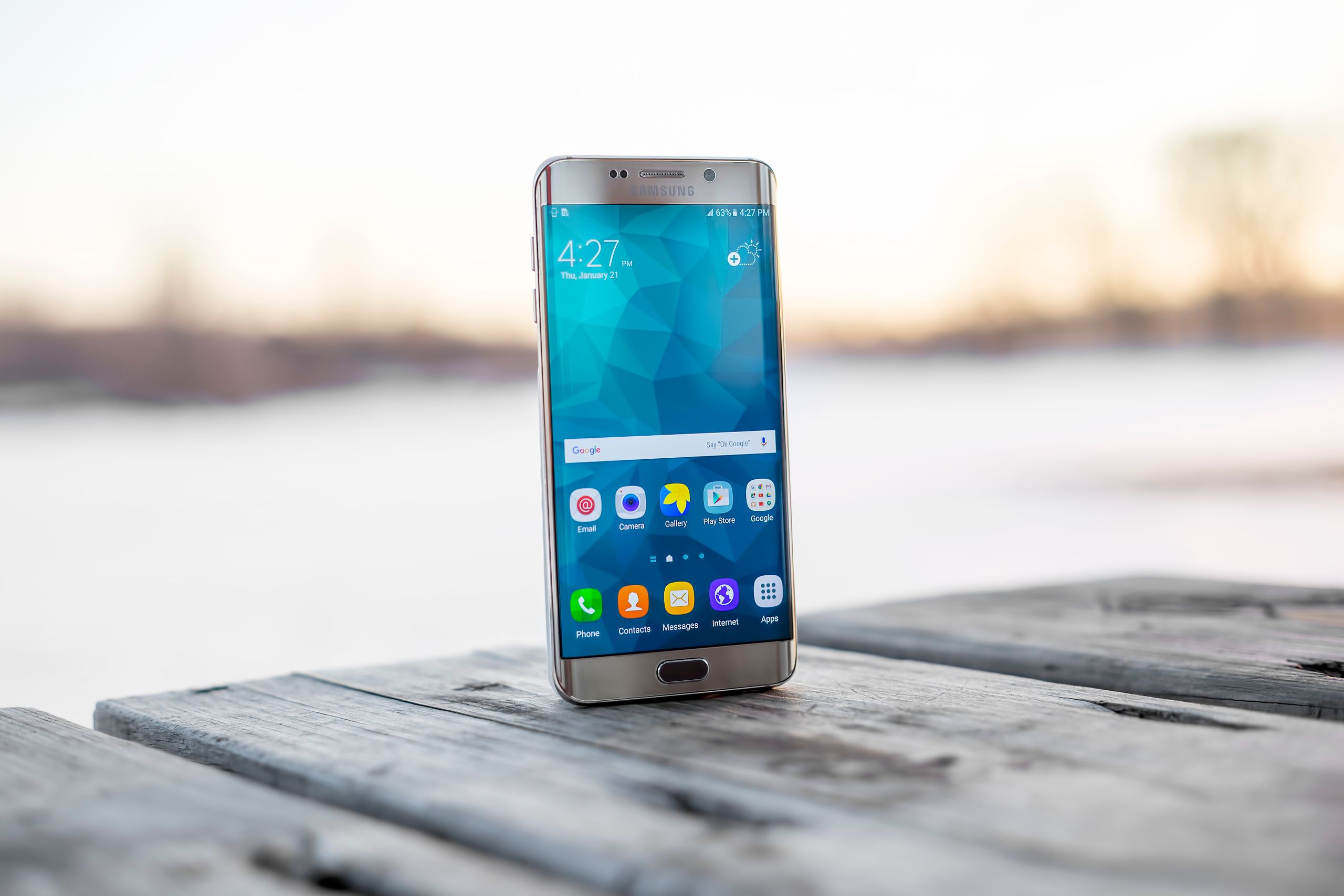 Samsung Smartphones Samsung smartphone placed on a wooden surface outdoors during sunset.
