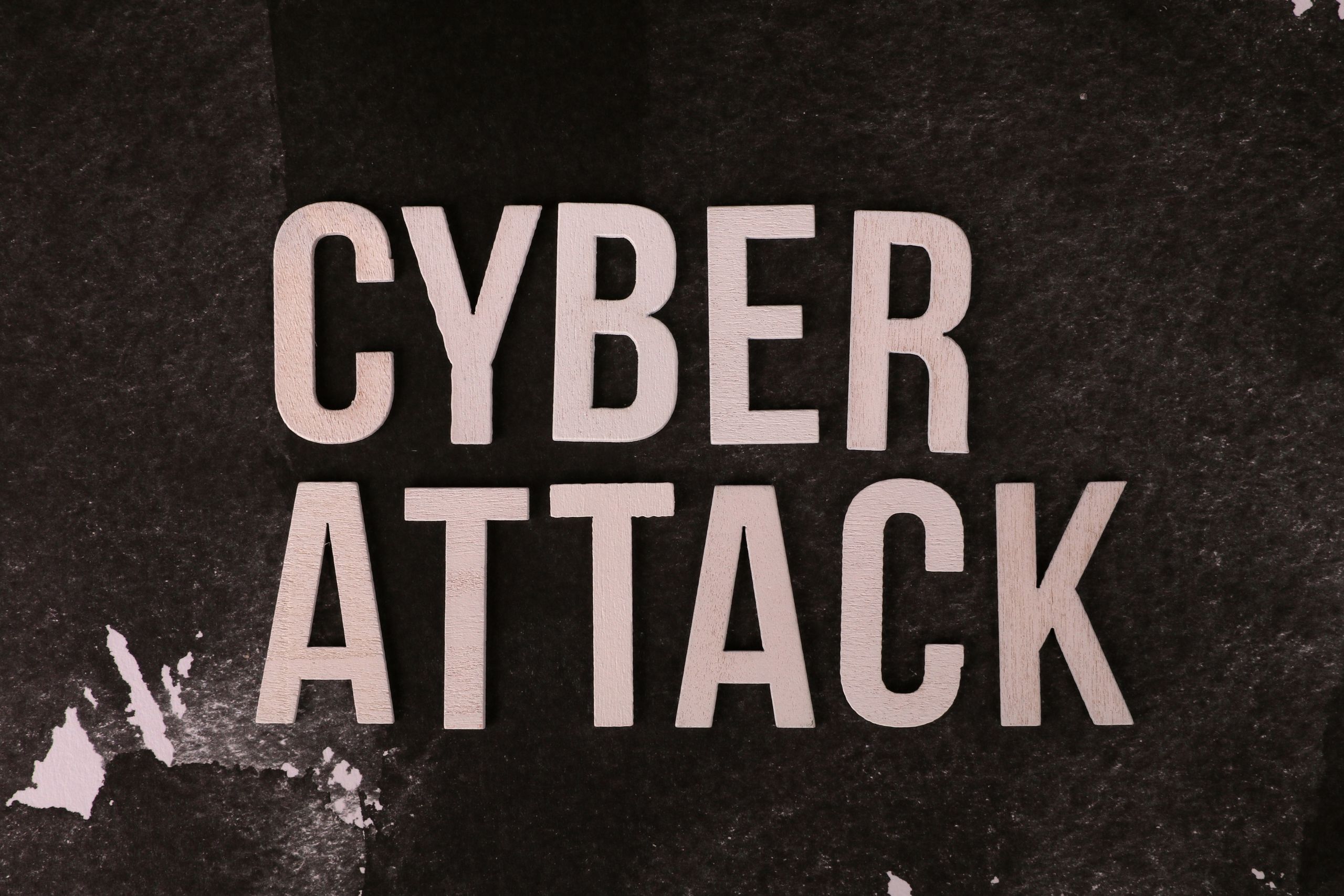 Text 'Cyber Attack' on textured dark paper highlights digital security threat concept.