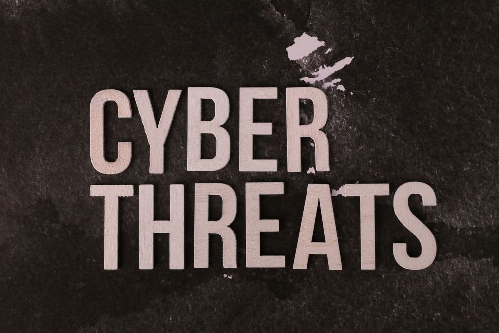The phrase 'Cyber Threats' displayed on a textured dark background, emphasizing digital security.