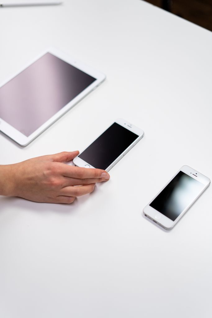 Top view of a minimalist setup featuring a tablet and smartphones on a white surface.